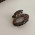 Detailed view of a vintage tortoiseshell acetate hair claw clip, small oval French hair accessory. - Blue Coffee