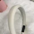 Detailed close-up shot of a sleek off-white padded headband on soft fur, with handmade inner label. - Off White