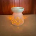 Vista di dettaglio del bruciatore per oli in ceramica con motivo floreale e calda luce. - Motivo a fuochi d'artificio