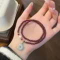 Close-up detail view of the elegant double-loop garnet beaded bracelet with jade pendant. - Safety Buckle