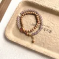 Gros plan détaillé de bracelets double couche en bois de santal et agate avec pendentif. - Style Caractère de Bon Augure