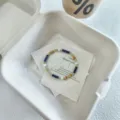 Primo piano dettaglio di un braccialetto impilabile di pietre preziose e perle su cartoncino. - Stile Lapislazzuli Giada Seta d'Oro