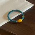 Close-up of Chinese retro style green abacus bead bracelet with yellow agate lulutong charm. - 6*2mm Wheel Bead Style