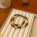 Detail shot of vintage tiger eye and crystal beaded layered bracelets displayed on tray. - 1 Double Loop With Yellow Crystal