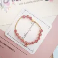 Close up of crackled crystal beaded bracelet detail, featuring gold heart and star charms. - 01 Watermelon Pink