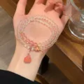 Detailed shot of multi-layer crystal and pink gemstone bracelet with delicate gold charm. - Watermelon Crystal Lotus Pod Multi-Strand Style