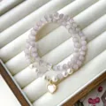 Close-up detail of double layer purple cat-eye stone bracelet with heart pendant and pearls. - Double Loop Heart Pendant