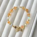 Vue rapprochée de perles d'agate pêche et de charm queue de poisson sur plateau velours - Style Queue de Sirène