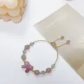 Close-up of sweet strawberry quartz and grey moonstone bracelet with delicate bow pendant detail. - Bow