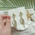 Detailed close-up of sparkling rhinestone angel wing drop earrings on white display card. - Angel Wings Long Dangle Style (HY1907)