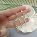 Detailed close-up shot of sparkling rhinestone music note dangle earrings held gently in hand. - Musical Note Long Dangle Style (HY1798-D4-F4)