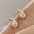 Close-up detail of the stylish gold ridged teardrop stud earrings, showcasing metallic texture. - 3D Rippled Teardrop Style (A24-109P)