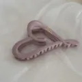Close-up view of a large matte mauve heart-shaped hair claw clip with delicate gold branding. - Heart Gold-Labeled Hair Claw / Pink