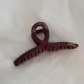 Close-up detail of the dark red matte hair claw clip featuring unique loop design and logo. - Hanger Gold-Labeled Hair Claw / Red