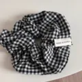 Detailed closeup of a classic black and white gingham fabric hair scrunchie with cute label. - Scrunchie / Black