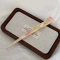 Detail shot of the elegant marbled acetate hair stick resting on a wooden tray. - Pink Green