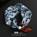Elegante pañuelo de seda azul con diseño paisley, gran hebilla de perla y detalle marrón. - Paisley Azul Café