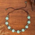 Detailed view of handmade ethnic beaded necklace with turquoise floral discs and brown cord. - Teal Patterned Disc Bead with Metal Spacer Style (C23-577)