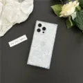 Detail shot of a square iridescent mother of pearl iPhone case with floral decor backdrop. - Square Shell Texture White / iPhone16
