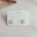 Close-up detail view of iridescent mermaid pearl stud earrings on a clean white card. - S / White