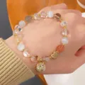 Close-up detail of crystal bead bracelet featuring cute ladybug pendant and gold heart charm. - Rutilated Quartz