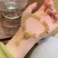 Close-up detail of a charming yellow crystal rutilated quartz bracelet with shell charm. - Citrine Shell Pendant Style