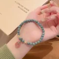 Close-up detail of the vintage jade stone bead bracelet featuring a cute pink pendant. - Strawberry Crystal Peace Buckle Style