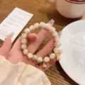 Detail shot of Chinese style gold foil glass bead bracelet with cute animal charms and coin. - Apricot White