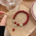 Gros plan détaillé du bracelet en perles rouges avec intercalaire en jade et charme Fu. - Style Simple Caractère Fu