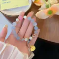 Vue de détail exquise d'un bracelet lotus de style chinois avec perles sculptées et breloques or. - Cristal Bleu