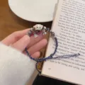 Ceramic lucky cat braided bracelet detail shot, cute woven cord with metal bell charm close-up. - Navy Blue Series