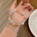 Closeup detail of the sweet pink glazed flower beaded bracelet with delicate golden accents. - Faceted Round Style