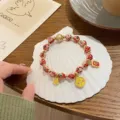 Detailed close-up of Chinese retro style cloisonne enamel beaded bracelet with gold charms. - Red Style (81629) / Red Series