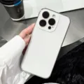 Close-up of white glass phone case held in hand, showing glossy edge and camera cutout. - Ivory / iPhone17promax