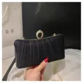 Close-up detail of black pleated evening clutch featuring sparkling rhinestone ring handle. - Black