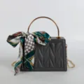 Dark grey structured handbag with gold handle, chain strap and elegant printed silk scarf accessory. - Gray