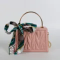 Pink box handbag with gold metal top handle, chain strap, and elegant printed silk scarf accent. - Pink