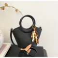 Black bucket bag with round handles and wooden bead charm, stylish cross-body handbag. - Black With Pendant
