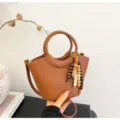 Brown pebbled leather bucket bag with top handle, chic beaded charm and crossbody strap for women. - Brown with Pendant