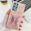 Primer plano detallado de la funda de teléfono rosa ondulada con soporte de mariposa brillante. - Estilo con Soporte de Mariposa / Para iPhone 13 / Ondas de agua - Rosa