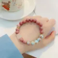 Close-up detail of the sweet gemstone beaded bracelet with pink stones and delicate crystal pendant. - 3 Lion Dance Style