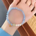 Close-up detail of light blue natural stone and pearl bracelet with gold pendant and jade bead. - Aquamarine with Artificial Pearl and Hetian Jade