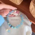 Natural stone beaded bracelet with sweet forest style blue beads and delicate floral pendant. - Aquamarine with Rainbow Stone and Shell Powder Lily