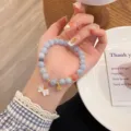 Detail shot of natural stone beaded bracelet with cute bow and bell charms, elegant aesthetic style. - Bow Pendant Style