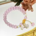 Gros plan detaille du bracelet de perles de cristal rose avec charmant pendentif de fortune. - Sac de Bénédiction / Rose