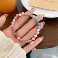 Close-up detail of colorful beaded bracelet with cute pearl and floral pendant charms. - Zirconia Flower Drop