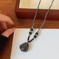 Black obsidian Buddha pendant necklace with woven cord and silver accents detail shot. - Buddha