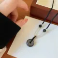 Gros plan du pendentif en obsidienne naturelle avec chaîne tressée élégante pour un style unique. - Boucle de sécurité