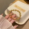 Close-up detail of vintage cloisonne enamel gold beaded bracelet with red butterfly charm. - 4 Blue Pink Flower Beads + Red Butterfly Beads