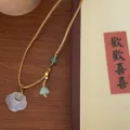 Close-up detail shot of a vintage Chinese style white agate ruyi pendant necklace with beads. - Khaki